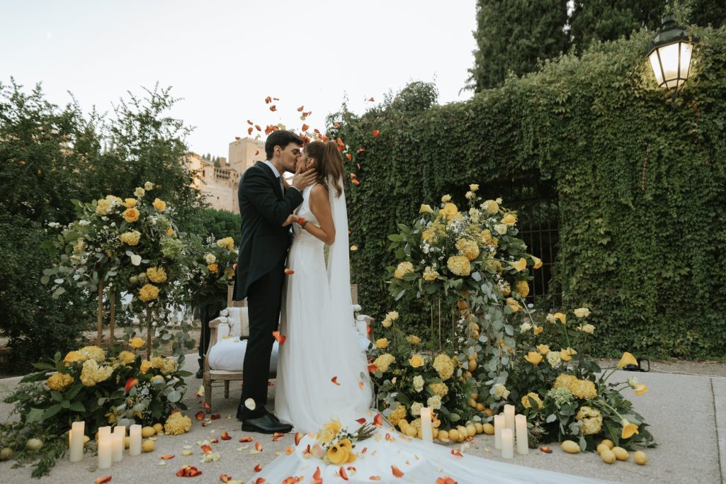 Boda civil Pareja de novios compartiendo un momento íntimo entre decoraciones florales.